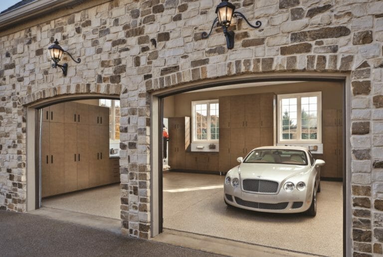 Stone-front two-car garage with one open bay and a white car parked inside.